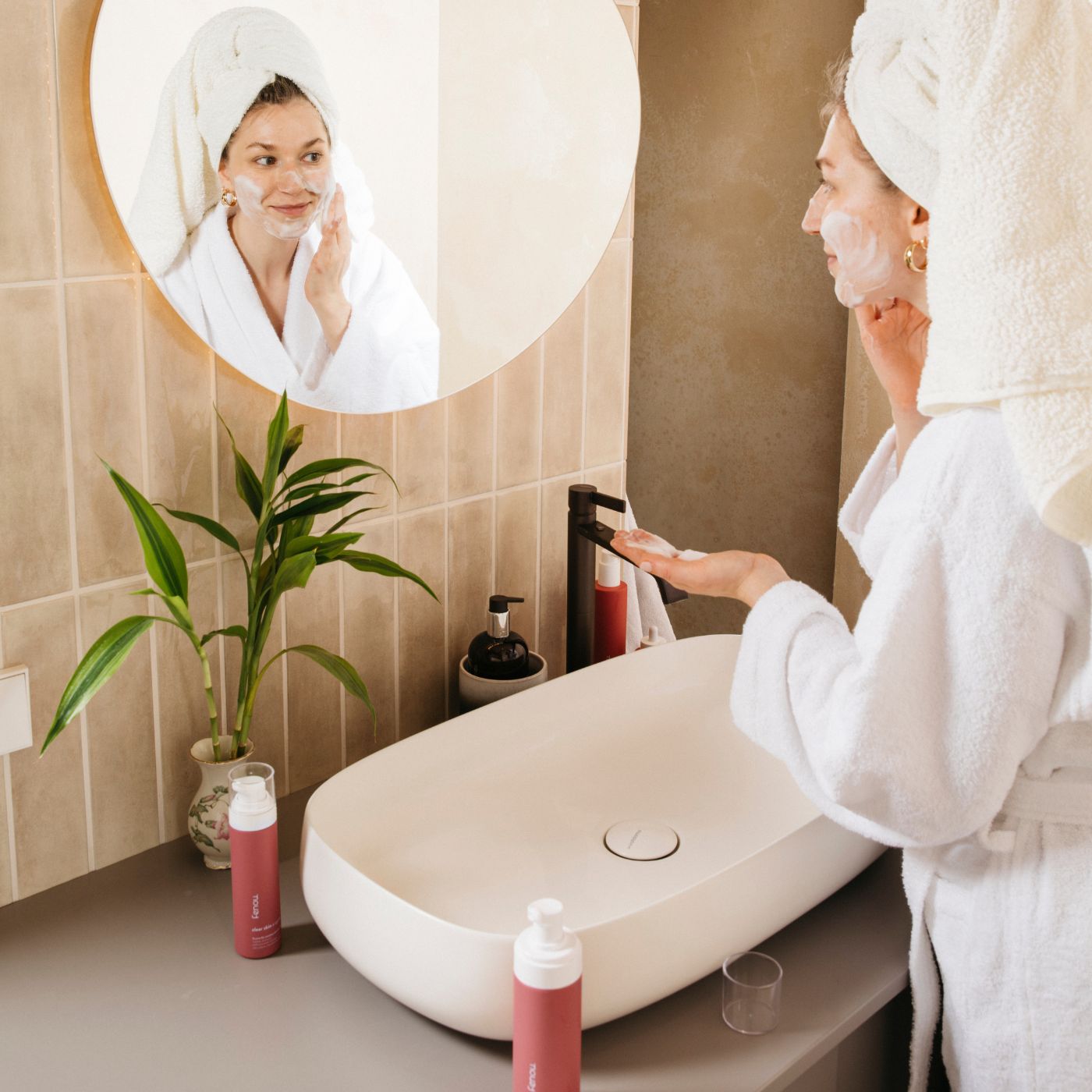 weiblich gelesene Person schäumt sich im Bad das Gesicht mit clear skin x cycle das Gesicht ein